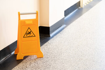 Caution wet floor orange fold out sign without text in a bright corridor, closeup detail Slipping...