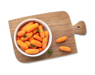Baby carrots in a bowl over wooden board with herbs isolated over white background