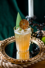 yellow coctail with orange on miror near candlestick