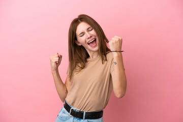 Young English woman isolated on pink background celebrating a victory