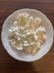 Homemade cottage cheese lies in a bowl, top view