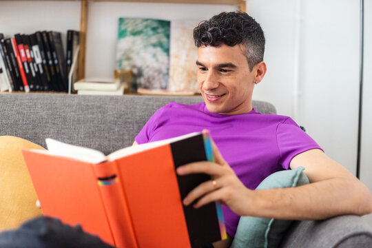 Transgender Man Reading Book Sitting On Armchair