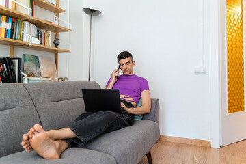 Transgender Man Using Phone And Laptop On Sofa
