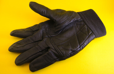 Black leather gloves in yellow background