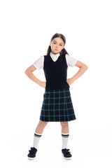 Fototapeta premium Serious schoolgirl standing in akimbo pose on white background.