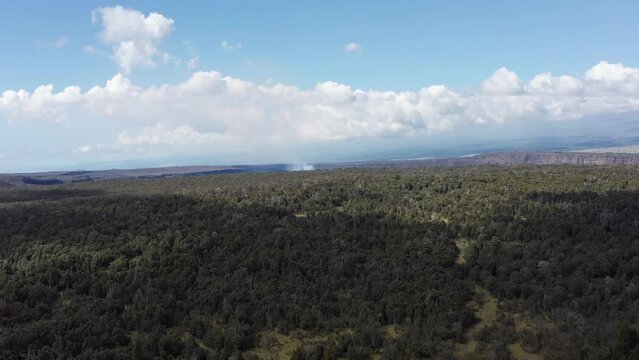 Wide aerial dolly shot of the Kilauea volcano with smoke rising from the caldera on the Big Island of Hawaii. 4K