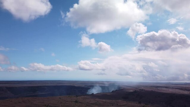 Handheld boom down shot from the sky to the smoking Kilauea volcano cauldron. 4K