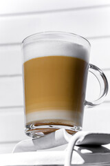 Glass of cappuccino with froth on a white can