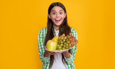 amazed child with fresh fruit plate on yellow background