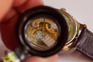 Inside og watch seen through magnifying glass at watchmaker. Close-up with selective focus.