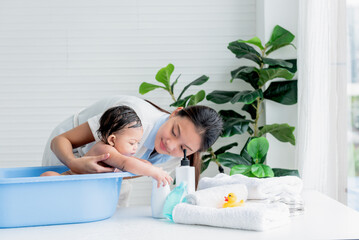 Obraz na płótnie Canvas Asian mother Bathing her 7 month old daughter, which the baby smiling and happy, with white background, to Asian family and baby shower concept.