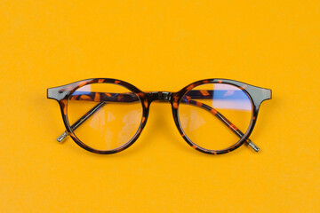 Stylish leopard-colored eyeglasses on an orange background
