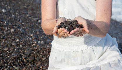 young girl in a white dress sits on the beach