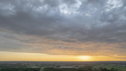 Aerial view amazing sunset over of the suburbs with the city under dramatic rain cloud. Global warming effect black thunderstorm dramatic rain clouds, dramatic sky, shot by a drone. High quality photo