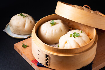 Asian food concept Chinese meat dumpling Baozi in dim sum bamboo steamer on wooden board on black...