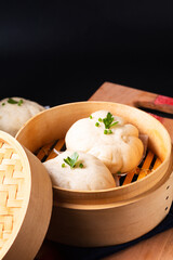 Asian food concept Chinese meat dumpling Baozi in dim sum bamboo steamer on wooden board on black slate stone background with copy space