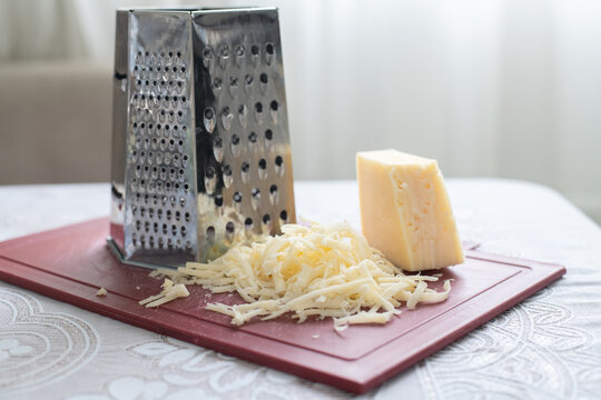 A pile of grated cheese on plastic board next to a grater