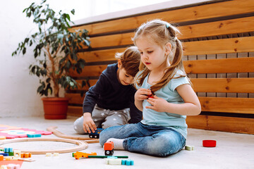 Little girl and boy sitting on floor and playing with constructor Bricks in kindergarten. Children playing games with toys in playroom. Interesting lesson for kindergartners developing intelligence