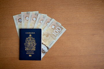 Calgary, Alberta - June 29, 2022: Canadian passport with Canadian 100 dollar bills.