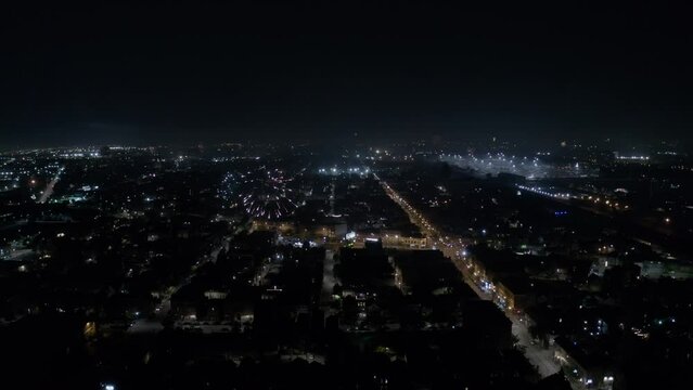Large amount of fireworks over several residential areas in Chicago while also several explosions on the horizon on a clear night during independence day. Drone dolly shot