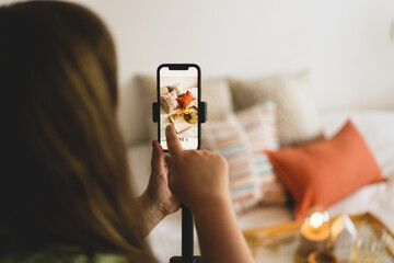 Video blog. A young woman is filming home goods for her online store on her phone camera. Running a video blog. A vlogger broadcasts online using a phone. Social networks,stay at home and quarantine.