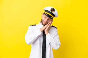 Airplane caucasian pilot isolated on yellow background making sleep gesture in dorable expression