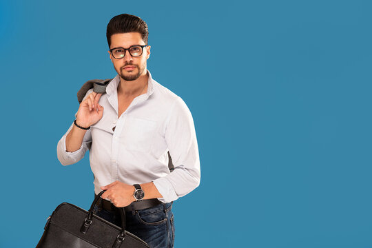 Handsome fashionable young businessman posing on blue studio background.