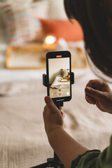 Video blog. A young woman is filming home goods for her online store on her phone camera. Running a video blog. A vlogger broadcasts online using a phone. Social networks,stay at home and quarantine.