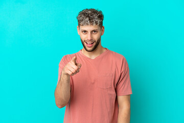 Young handsome caucasian man isolated on blue background surprised and pointing front