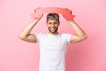 Young handsome caucasian man isolated on pink background holding an empty placard