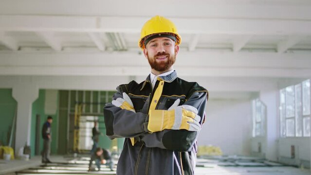 At large construction site inside of the building walking to the camera one of construction worker he posing in front of the camera and smiling large