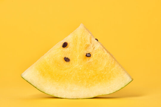 One piece of yellow watermelon with seeds on yellow background, delicious refreshing fruit