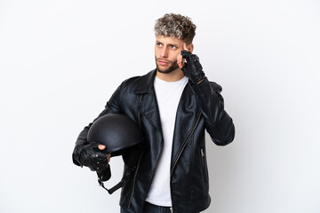 Young man with a motorcycle helmet isolated on white background having doubts and thinking