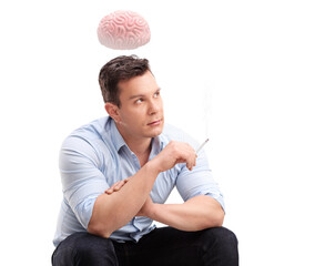 Nervous young man smoking a cigarette and brain floating above his head
