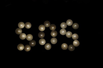 sos save our souls written with burning candles isolated on black background