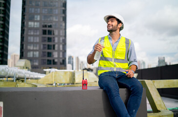 Caucasian professional engineer or technician sit on terrace of construction with relax after work and look around with happiness for success of the project.