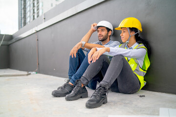 Obraz na płótnie Canvas Couple professional engineer or technician sit on the floor of terrace of construction site during relax after work and talk together and they look happy.