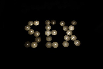 word sex written with burning candles isolated on black background