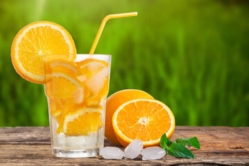 Natural lemonade with mint and fresh oranges on wooden table.