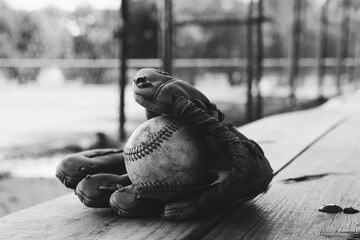Baseball dugout bench with ball and glove in black and white.