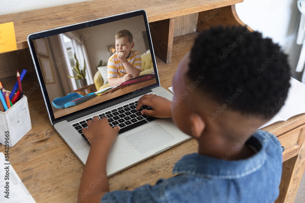 Canvas Prints African american boy looking at caucasian student on laptop screen during online class at home