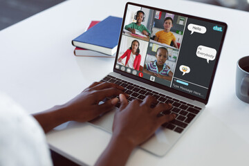 Cropped hands of african american studying typing message on laptop during online class at home