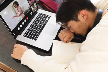 Foto op Plexiglas Aziatische plekken Hoge hoekmening van Aziatische jongen die slaapt tijdens online lezing via videogesprek op laptop thuis