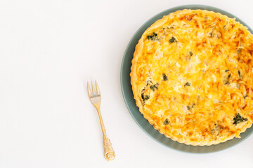 An open box with a chicken pie and a golden fork stands on a white table.