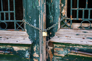 Wooden shabby door locked with padlock. The doors of the old house are locked. Property locked with chain.