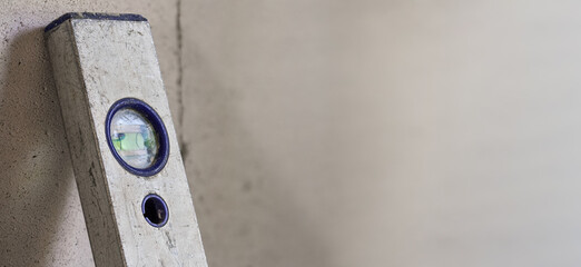 Worn aluminium spirit bubble level placed next to wall in construction site, empty space for text...