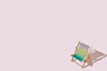 Mini colourful beach deck chair with sharp shadow against pink background. Creative summer concept with a copy space. Minimal relax and vacation idea.