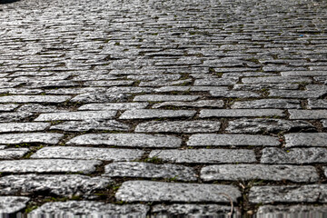 Ancient paving stones on a city street. An ancient paved street. Old city street. Daytime on a sunny day.