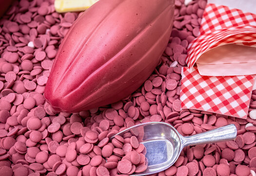 Ruby chocolate cocoa fruit against the background of ruby chocolate drops top view.
