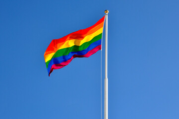 The gay pride flag against blue sky